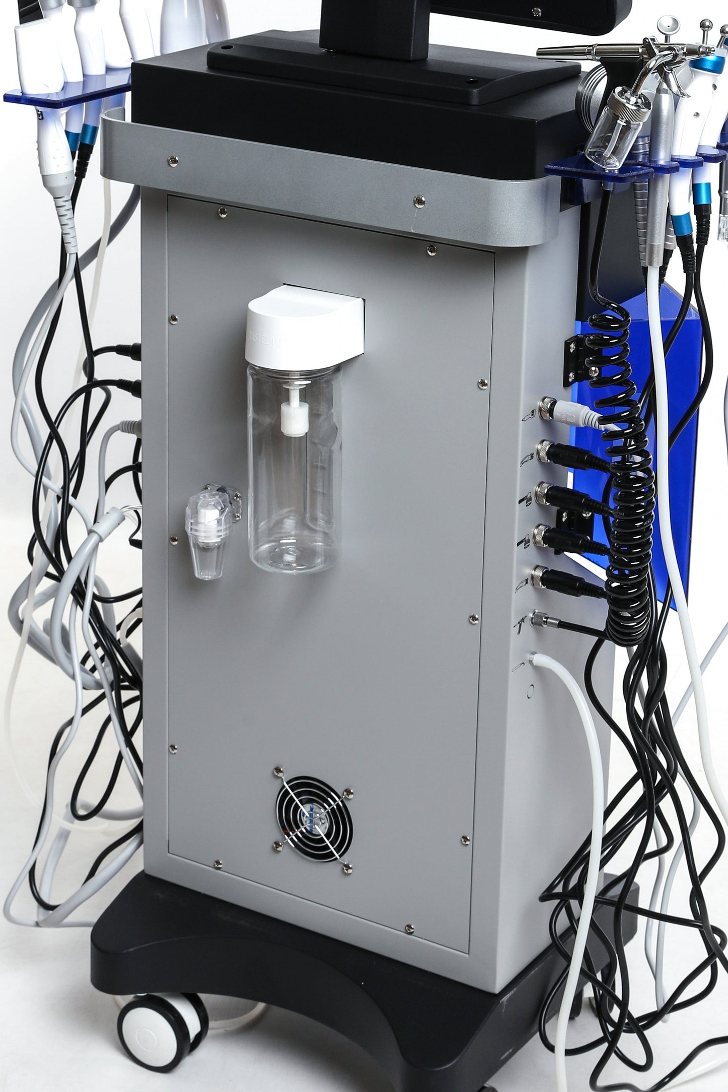 Back view of Hydra Smart Beauty facial machine showing fluid containers, power ports, and cable connections